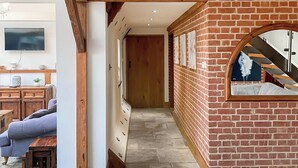 Un couloir doté d’un sol en pierre, de poutres en bois, d’un mur en briques et d’un escalier agrémenté d’un miroir.