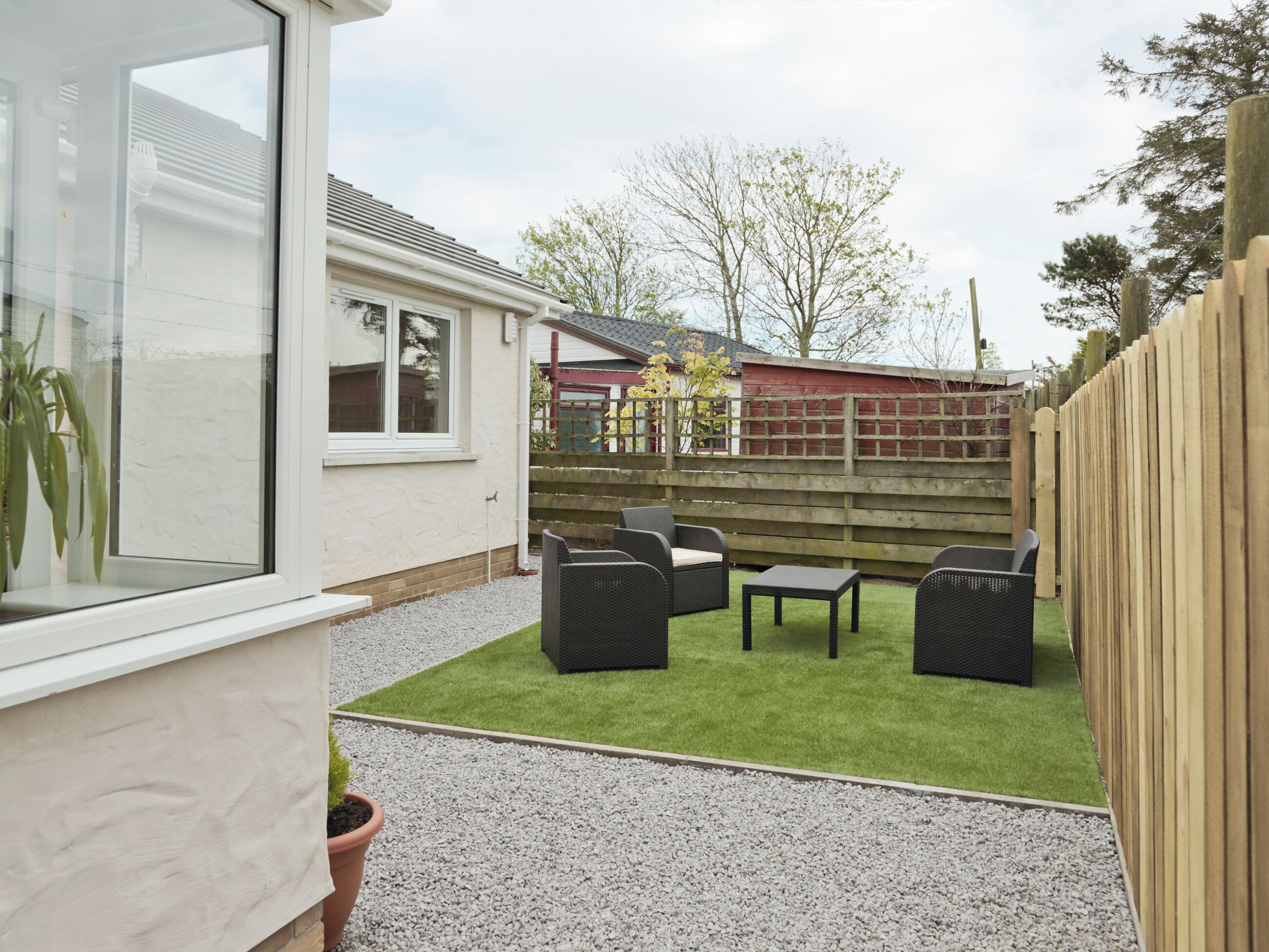 A patio with outdoor furniture, a small table, and a potted plant.