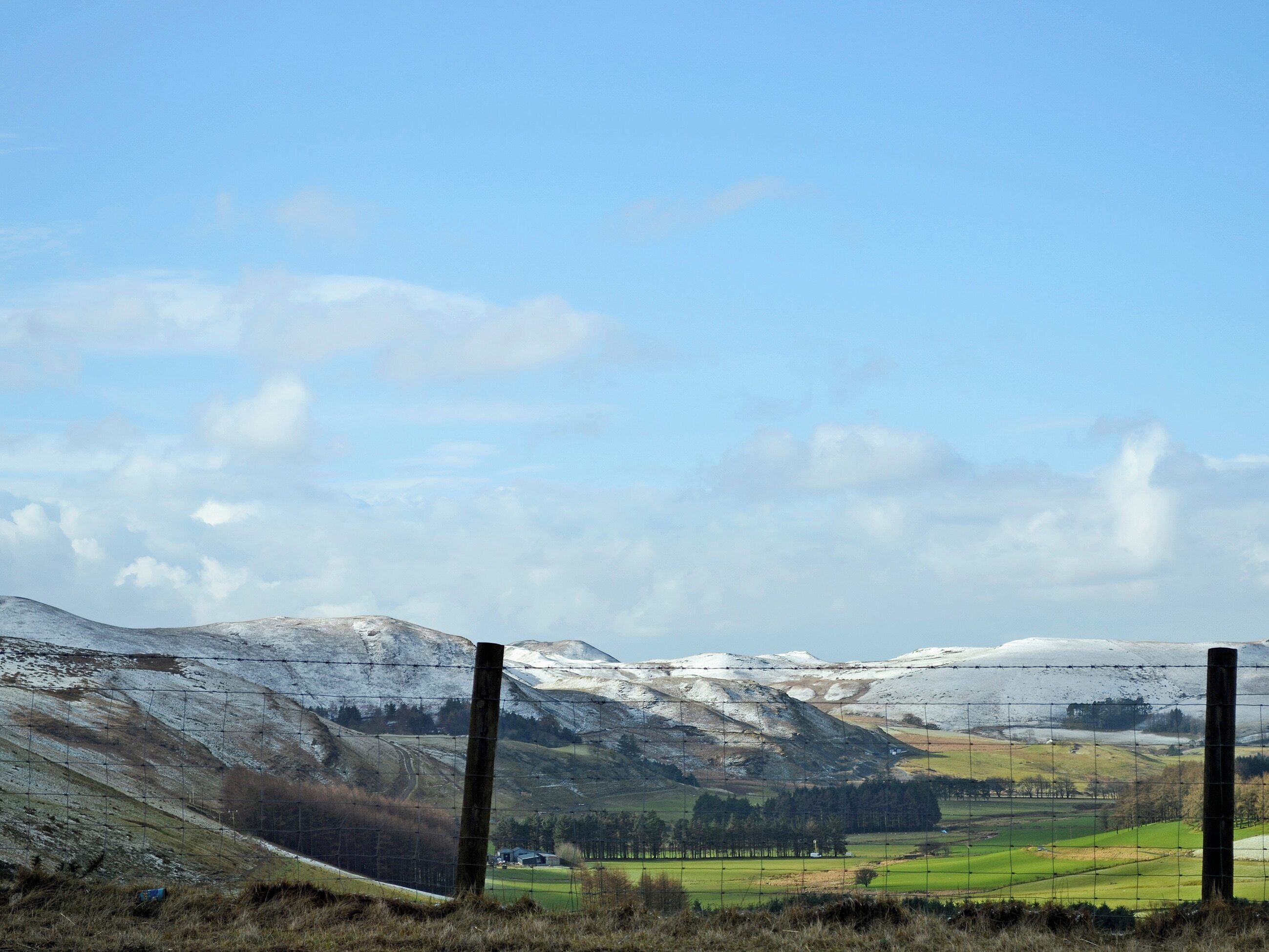 Een omheind landschap met besneeuwde heuvels en een heldere lucht.