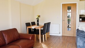 Ein Wohnzimmer mit einem braunen Ledersofa, einem Holzesstisch mit Stühlen und einer Tür mit Spiegel.