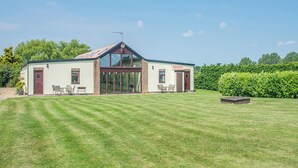 Une maison à deux étages avec une grande porte d’entrée en verre, une antenne parabolique et une pelouse bien entretenue.