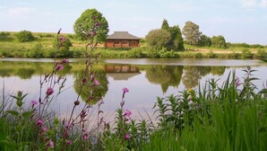 A cabin by a lake with a reflection, surrounded by greenery and trees. - 2 bedroom accommodation in Hagworthingham (Hagworthingham)