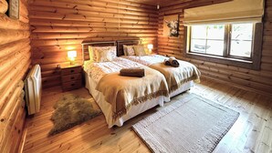 A cozy log cabin bedroom with a bed, bedside lamps, a window, and a rug. - 2 bedroom accommodation in Hagworthingham (Hagworthingham)
