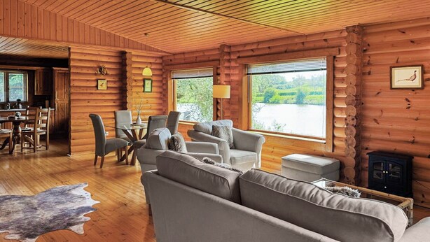A log cabin interior with a sofa, chairs, a dining table, and a fireplace. - 2 bedroom accommodation in Hagworthingham (Hagworthingham)
