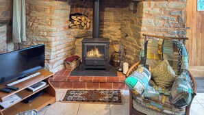 A cozy living room with a stone fireplace, a television, and a comfortable seating area. - 1 bedroom accommodation in Bircher Common, near Leominster (Bircher Common, near Leominster)