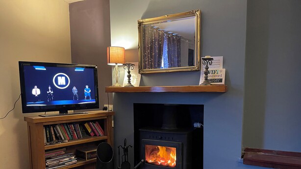 A living room with a television, bookshelves, a fireplace, and a mirror. - 2 bedroom accommodation in Staithes, near Whitby (Staithes, near Whitby)