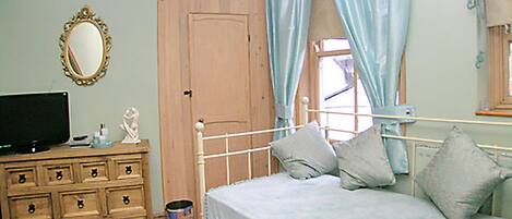A bedroom with a bed, dresser, mirror, and a television.