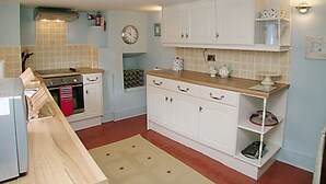 A compact kitchen with white cabinets, a wooden countertop, and a clock on the wall. - 2 bedroom accommodation in Staithes, near Whitby (Staithes, near Whitby)
