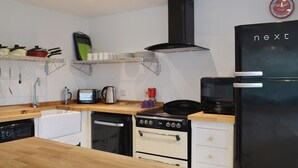 Una cucina moderna con un piano di lavoro in legno, un frigorifero nero, un fornello, una lavastoviglie e una macchina per il caffè.