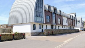 A modern building with a curved glass facade and a stone wall entrance. - 2 bedroom accommodation in West Bay, near Bridport (West Bay, near Bridport)