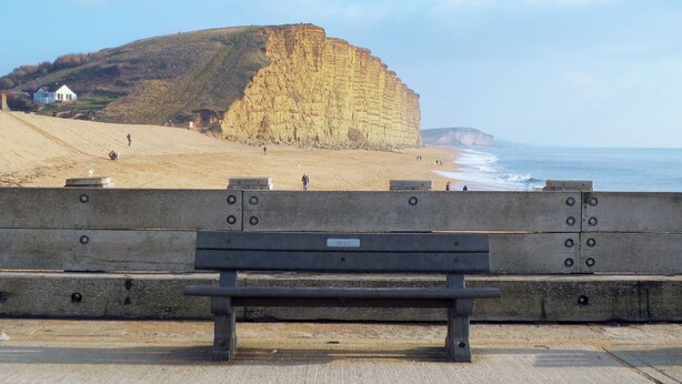 A bench overlooking a beach with cliffs in the background. - 2 bedroom accommodation in West Bay, near Bridport (West Bay, near Bridport)