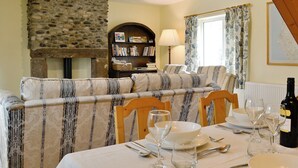 A dining area with a stone wall, a sofa, a bookshelf, and a table set for a meal. - 2 bedroom accommodation in Croasdale, near Ennerdale Lake (Croasdale, near Ennerdale Lake)