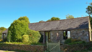 A stone building with a sloped roof, a wooden fence, and a large tree in the foreground. - 1 bedroom accommodation in Michaelstow, near Camelford (Michaelstow, near Camelford)