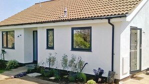 A single-story house with a tiled roof, white exterior walls, and a small front garden with various plants. - 3 bedroom accommodation in Brancaster Staithe, near Hunstanton (Brancaster Staithe, near Hunstanton)