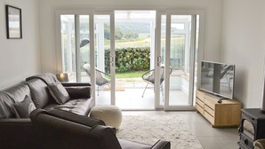 A modern living room with a leather sofa, a flat-screen TV, and a fireplace. - 3 bedroom accommodation in Brancaster Staithe, near Hunstanton (Brancaster Staithe, near Hunstanton)