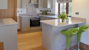 Una cocina moderna con una isla, horno empotrado e iluminación colgante.
