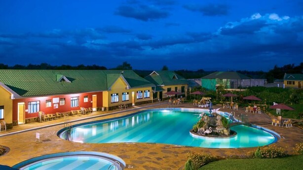 A hotel with a large swimming pool, outdoor seating areas, and a well-lit building facade. - Nice Digital Hotel Mwea (Nairobi)