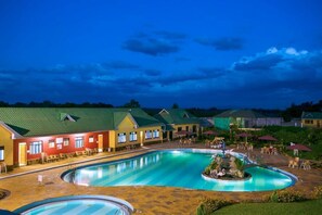 Un hôtel doté d’une grande piscine, d’espaces extérieurs aménagés et d’une façade bien éclairée.