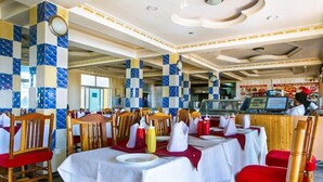 A restaurant with tables set for dining, wooden chairs, and a counter with a menu. - Nice Digital Hotel Mwea (Nairobi)