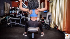 A person using a pull-up bar in a gym with various exercise equipment. - Nice Digital Hotel Mwea (Nairobi)