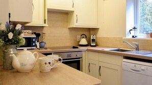 Una cucina con mobili bianchi, un forno a microonde, un bollitore, un lavello e una lavastoviglie.