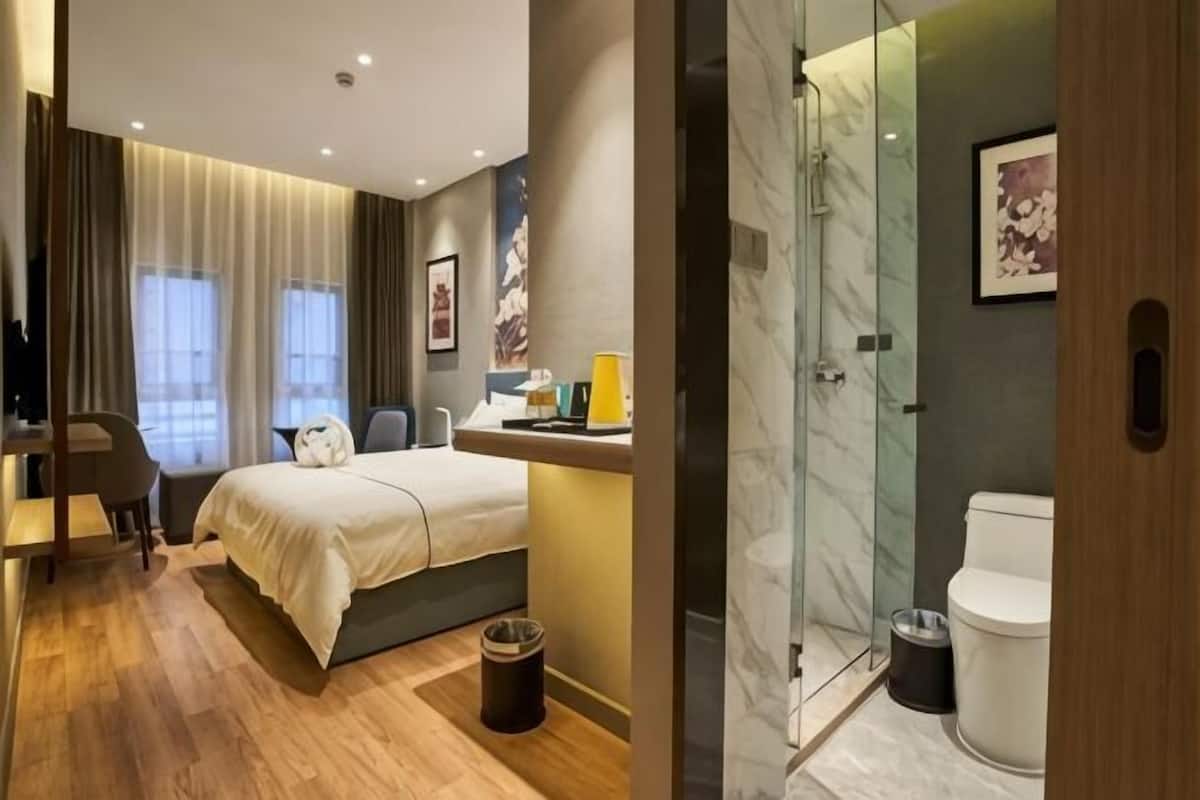 Ein modernes Hotelzimmer mit Bett, Schreibtisch und Duschbereich.