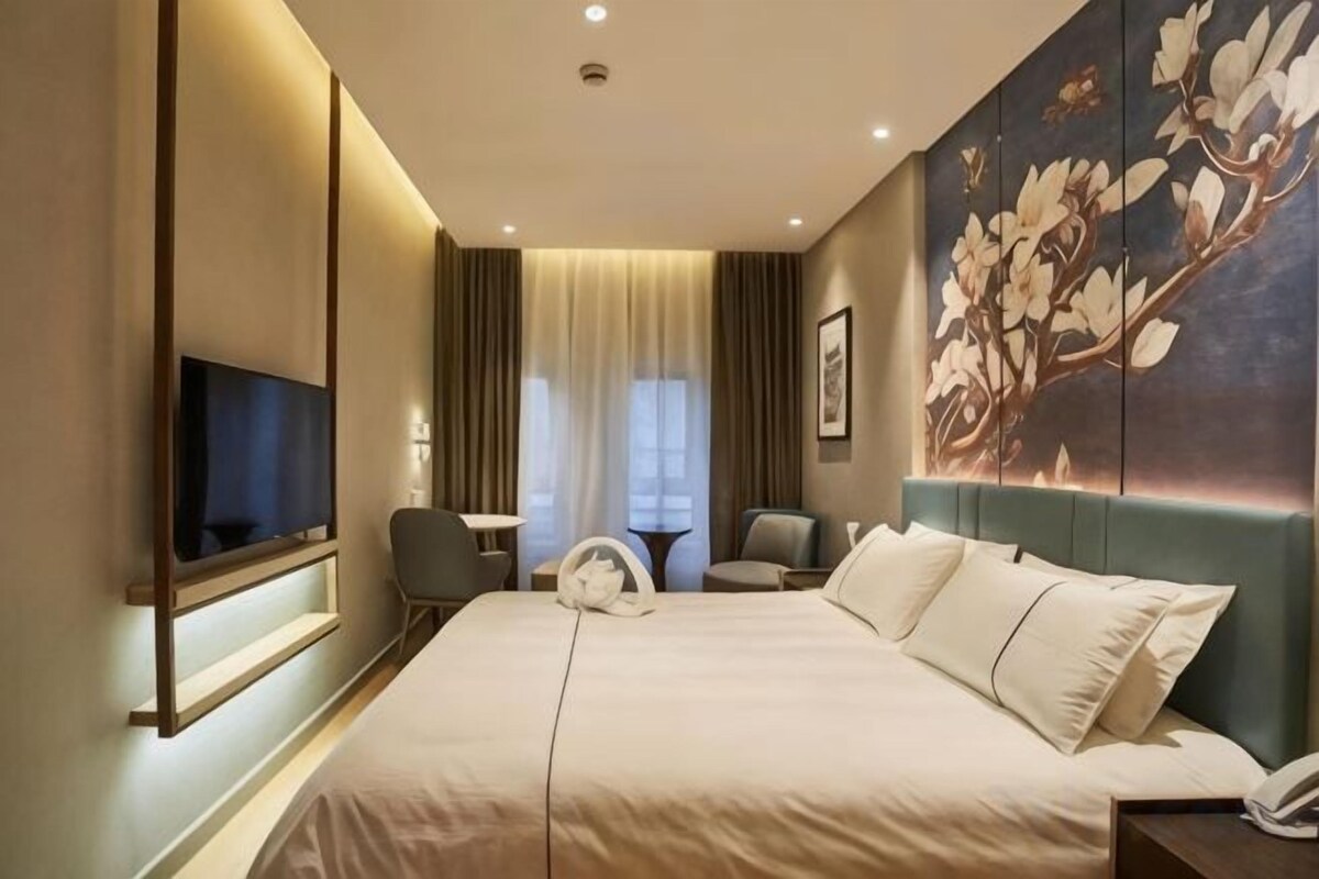 Une chambre d’hôtel avec un grand lit, un téléviseur à écran plat, un bureau et une chaise.
