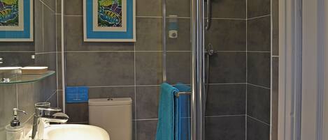 A bathroom with a glass shower enclosure, a white sink, and a toilet.