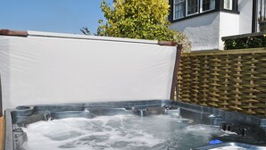 Una vasca idromassaggio con struttura in legno, coperchio bianco e telaio metallico.