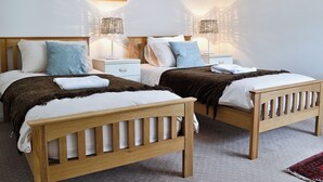 A double room with two wooden beds, white bedding, and a painting on the wall. - 4 bedroom accommodation in Wern-y-Wylan (Wern-y-Wylan)
