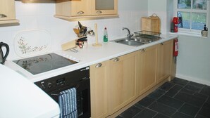 Cucina con mobili in legno, cappa in acciaio inossidabile, forno integrato, lavastoviglie e finestra con vista esterna.
