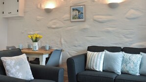 En moderne stue med en grå sofa, et træspisebord og en vase med gule blomster.
