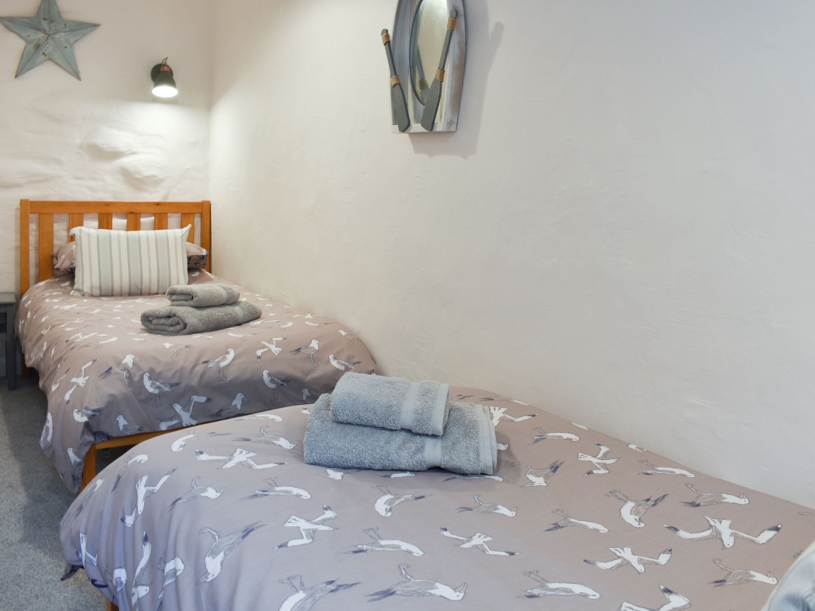 A bedroom with two single beds, each with a patterned duvet and pillows, a wooden headboard, and a star decoration on the wall.