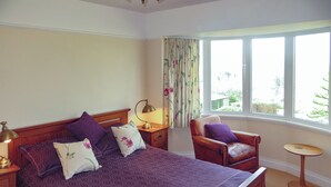 A bedroom with a large bed, a chair, a small table, and a window with curtains. - 4 bedroom accommodation in Portinscale, near Keswick (Portinscale, near Keswick)