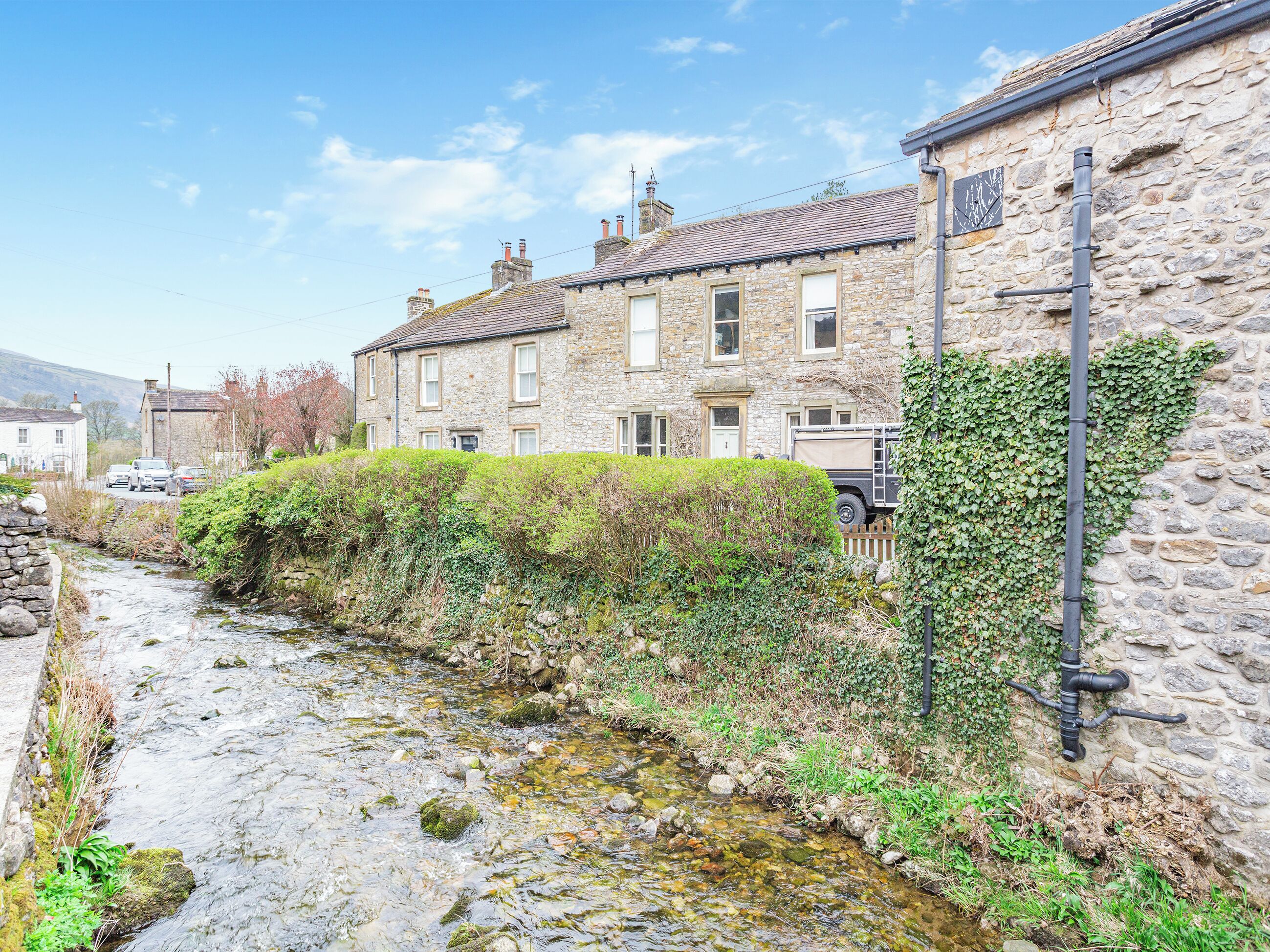 A stone building with a stone wall and a small stream running alongside it.