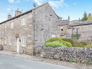 A stone building with a door and windows, a stone wall, and a small garden. - 2 bedroom accommodation in Kettlewell (Kettlewell)