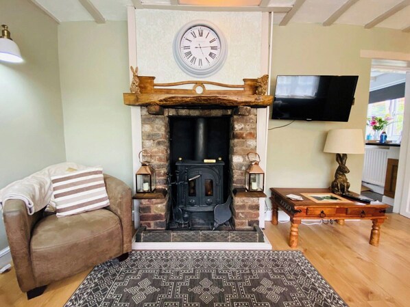 A cozy living room with a fireplace, a sofa, a patterned rug, and a television mounted on the wall.
