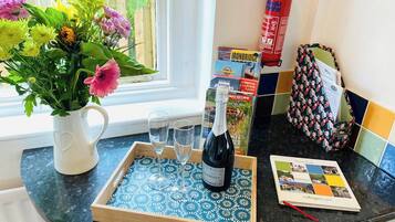 Un comptoir de cuisine sur lequel se trouve un plateau avec une bouteille de vin, deux verres et un bouquet de fleurs.