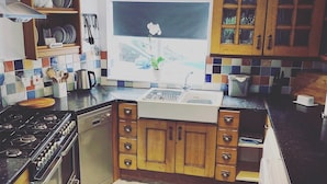 Een keuken met houten kastjes, een fornuis, een spoelbak en een raam met uitzicht op het landschap.