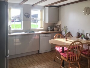 A kitchen with a sink, a dishwasher, a window, and a dining table with chairs.