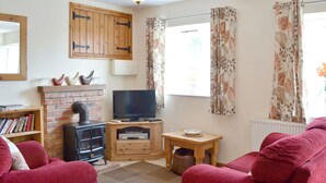 A living room with a fireplace, television, and red sofas.