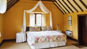 A bedroom with a four-poster bed, a window with curtains, bedside tables with lamps, and a wall-mounted heater. - 2 bedroom accommodation in Cradley, Malvern (Cradley, Malvern)