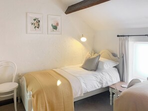 A bedroom with a bed, bedside table, chair, and two framed botanical prints on the wall. - Grain End Cottage is set in large landscaped gardens. (Sawdon, near Scarborough)