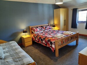 Un dormitorio con cama, mesita de noche, armario y ventana.