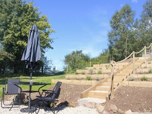 Een tuin met een tafel en stoelen, een parasol en een houten trap.