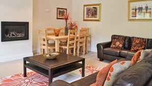 A living room with a dining table, chairs, a coffee table, a sofa, and a fireplace. - 4 bedroom accommodation in Alvechurch (Alvechurch)