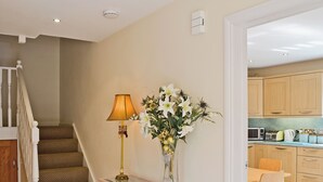 A staircase with patterned carpet, a glass console table with magazines, a lamp, and a vase with flowers. - 4 bedroom accommodation in Alvechurch (Alvechurch)