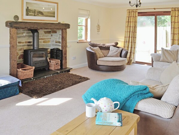 A cozy living room with a stone fireplace, a comfortable sofa, a wooden coffee table, and a bookshelf.