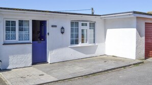 Een gelijkvloers huis met een blauwe deur, witte buitenmuren en een rode garagepoort.