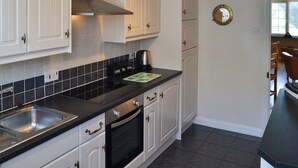 Een keuken met witte kastjes, een zwart aanrecht, een roestvrijstalen spoelbak en een inbouwoven.